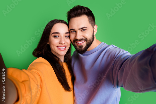 Photo of cheerful glad charming couple wear trendy clothes take selfie isolated on green color background photo