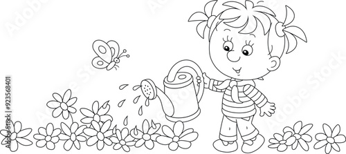 Happy little girl watering garden flowers on a pretty small flowerbed