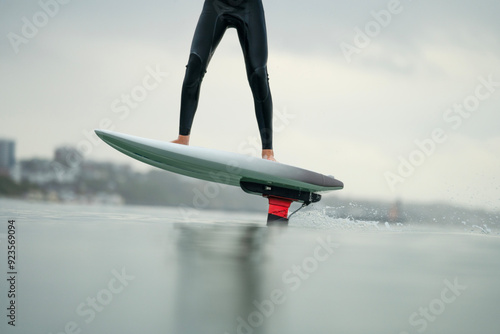 Close up of an man's legs standing on riding an electric powered hydrofoil board, efoil foil drive hybrid foil.