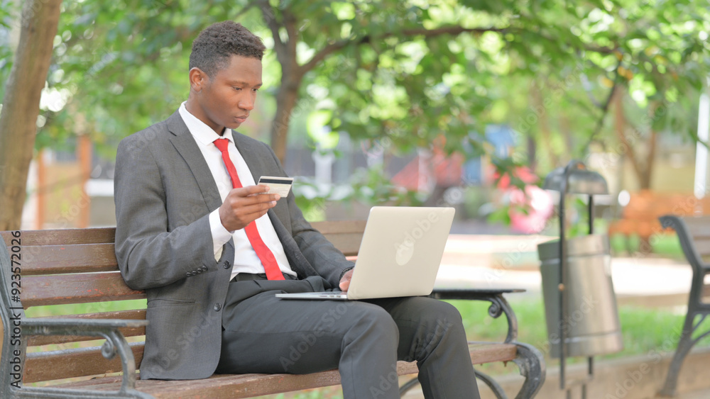 African Man Enjoying Online Shopping with Laptop in Lap Outdoor African Man Enjoying Online Shopping with Laptop in Lap Outdoor