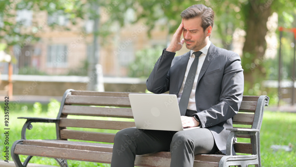 Middle Aged Businessman with Migraine Using Laptop while Sitting Outdoor on Bench Middle Aged Businessman with Migraine Using Laptop while Sitting Outdoor on Bench