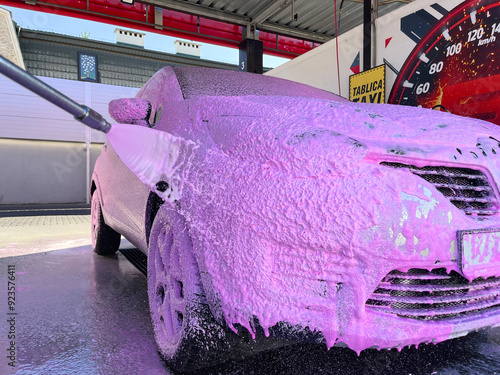 Washing a silver car using pink active foam at a car wash photo