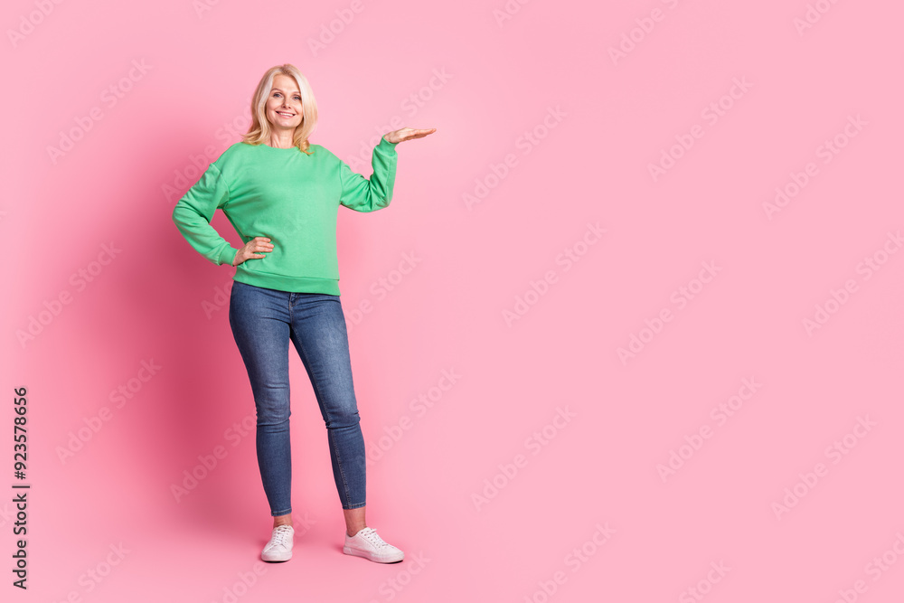 Full length photo of lovely senior lady measure size empty space dressed stylish green garment isolated on pink color background Full length photo of lovely senior lady measure size empty space dressed stylish green garment isolated on pink color background