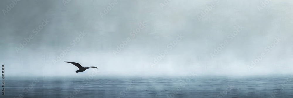 Fototapeta premium Elegant lone bird soaring against an expansive gray sky in a peaceful expression of freedom