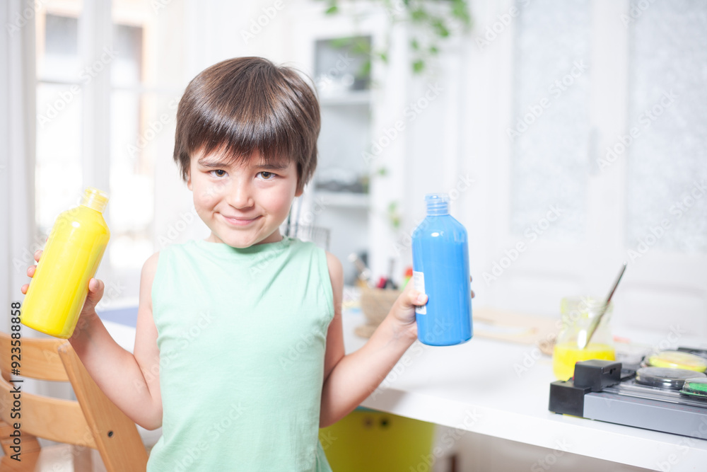 Portrait of a boy holding two pots of paint that he will use in his craft that he makes in his living room at home. Portrait of a boy holding two pots of paint that he will use in his craft that he makes in his living room at home.