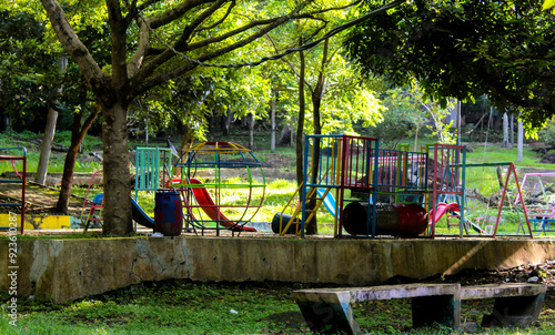 Selective focus of an abandoned playground in a city park containing a red slide, a scary or eerie or creepy atmosphere.