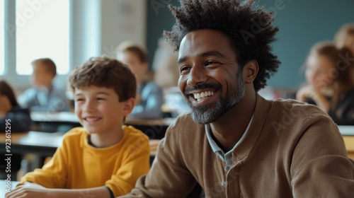 A smiling teacher interacts with a young student, fostering excitement and curiosity in a bright classroom filled with attentive learners