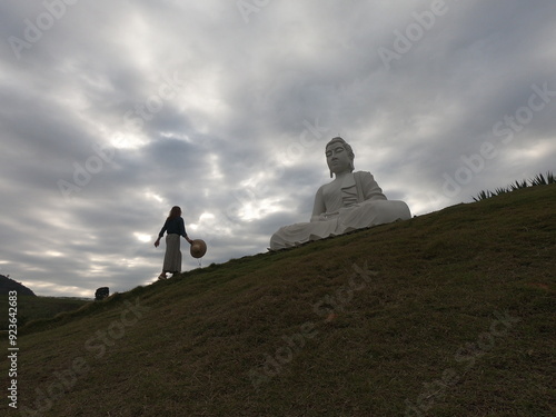 turista em mosteiro em ibiraçu, espirito santo, ao lado de estatua de buda photo