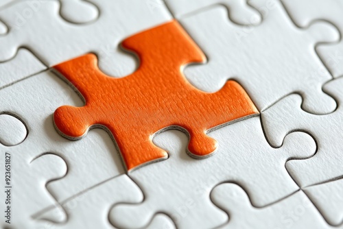 Picture of an orange puzzle piece that fits into a white puzzle. Teamwork, solutions, and problem-solving concepts are emphasized