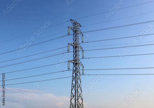 Selective focus of High voltage towers or power line tower with a background of bright blue sky with clouds during the day photo