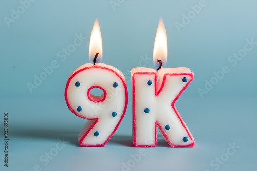 Candles shaped like 9k, white with pink outlines, blue dots, glowing flames. photo