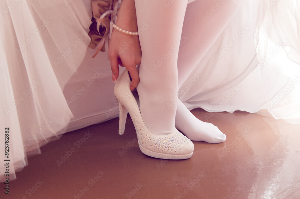 Bride getting ready for the wedding ceremony putting on elegant white wedding shoes. Bride getting ready for the wedding ceremony putting on elegant white wedding shoes.