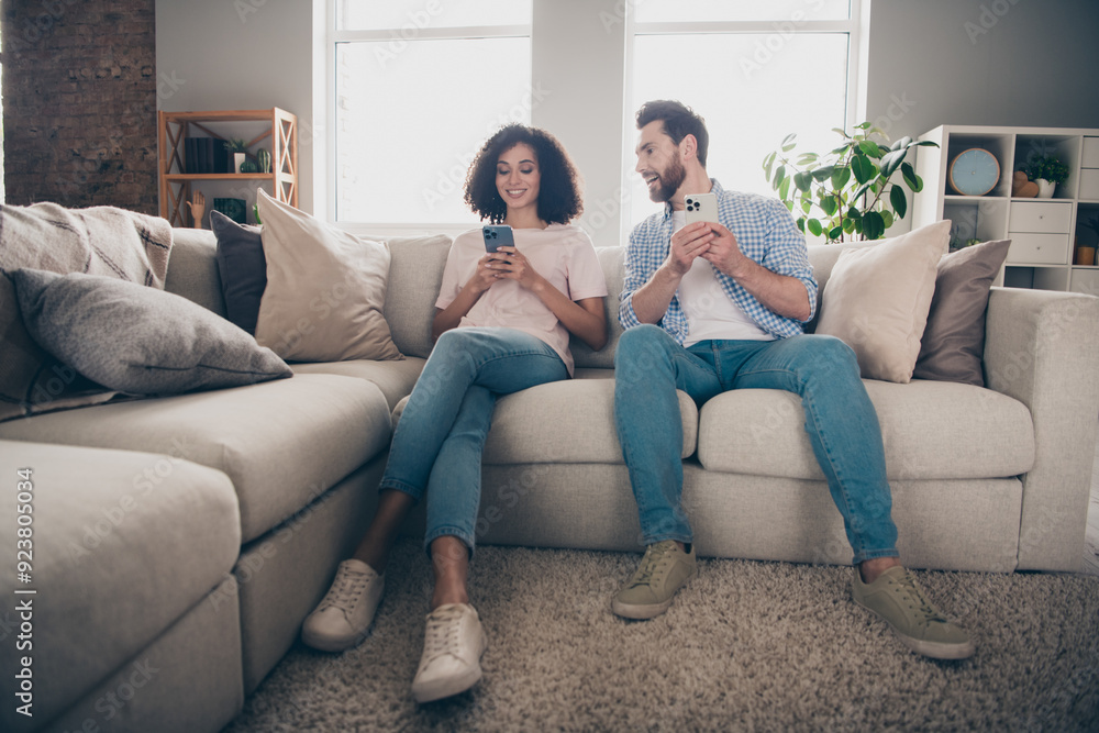 Photo of positive girl guy sit couch using smart cell gadget in room indoors Photo of positive girl guy sit couch using smart cell gadget in room indoors