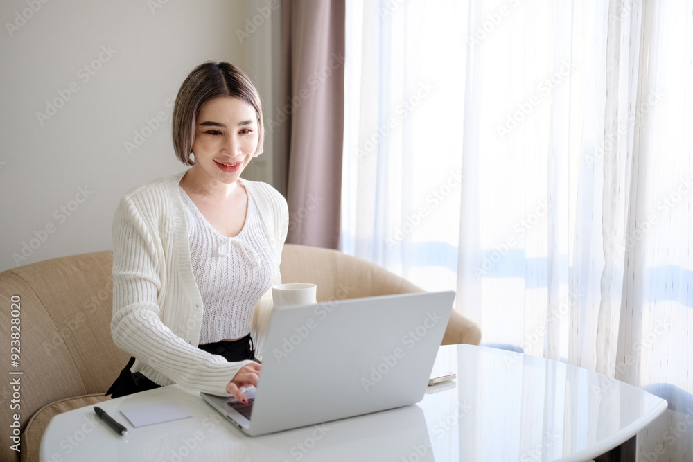 A woman is sitting at a table with a laptop and a cup of coffee A woman is sitting at a table with a laptop and a cup of coffee