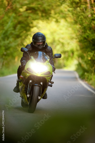 Canvas Print motorcyclist riding a green motorcycle on an asphalt road