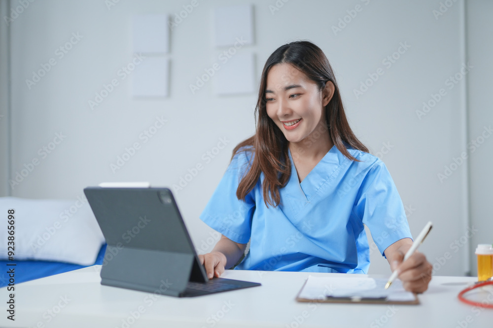 Smiling doctor is using a digital tablet and taking notes during an online consultation in a hospital room Smiling doctor is using a digital tablet and taking notes during an online consultation in a hospital room
