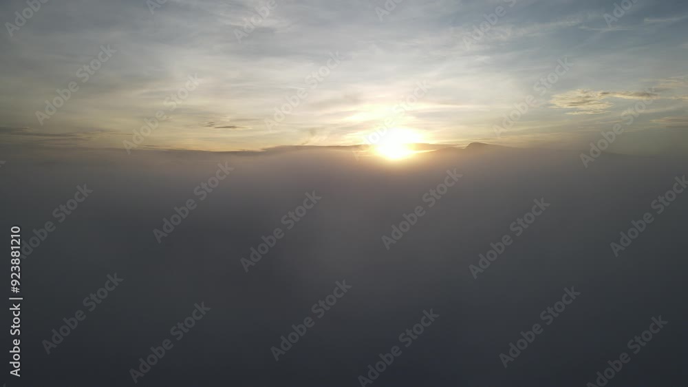 Aerial view through the clouds flowing with mountains in the background Aerial view through the clouds flowing with mountains in the background