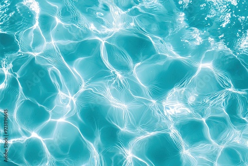 Clear turquoise swimming pool water with sunlit ripples creating wavy abstract pattern on surface. Perfect for background, relaxation and outdoor related content.