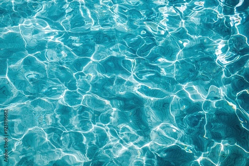 Clear turquoise water in pool with sun ripples creating wavy abstract pattern on surface. Perfect for background, relaxation and outdoor recreation.