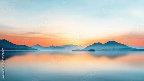 Serene landscape at sunrise with mountains reflecting on calm water, creating a peaceful and tranquil atmosphere.