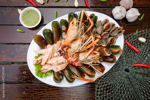 Seafood plate with shrimp shellfish crab squid cockle spotted babylon with seafood sauce chili lemon lime serve on dining table photo