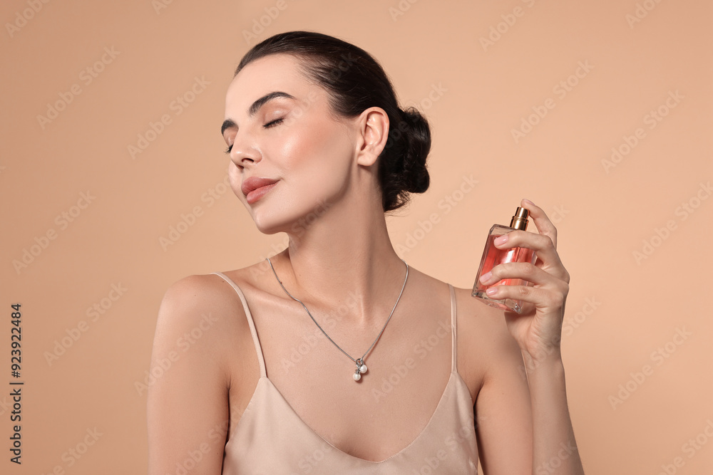 © New Africa - Beautiful woman spraying perfume on beige background