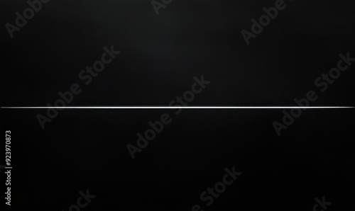 A long, thin object is shown in a black background. The object is silver and he is a wire. The image has a dark and moody atmosphere, with the black background emphasizing the object's thinness