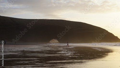 Surfer at Sunset on Scenic Beach with Coastal Arch in Morocco, Legzira Beach. photo