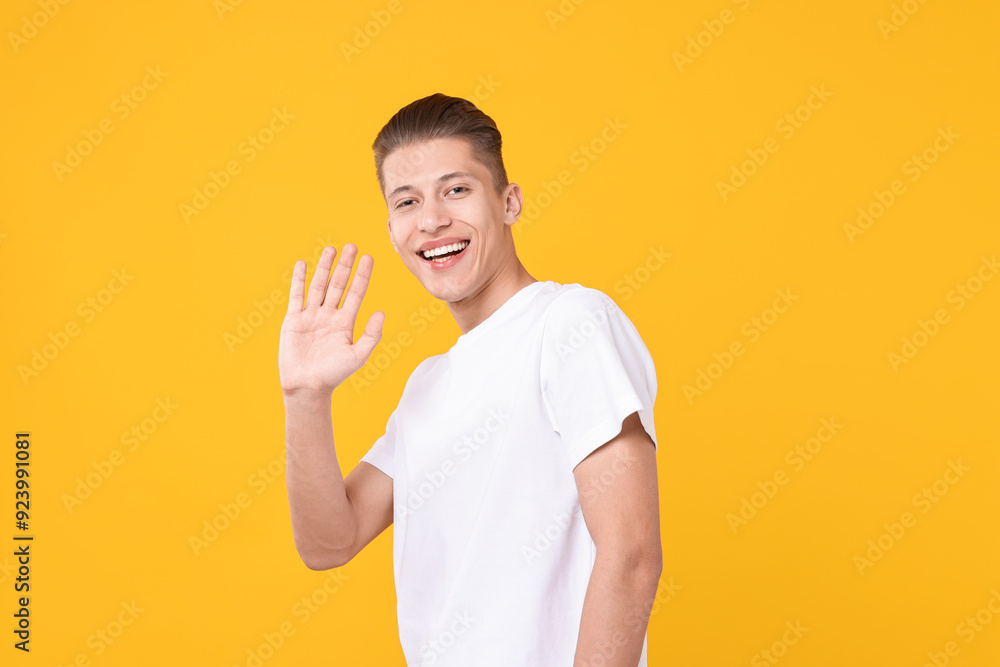 Goodbye gesture. Happy young man waving on orange background Goodbye gesture. Happy young man waving on orange background