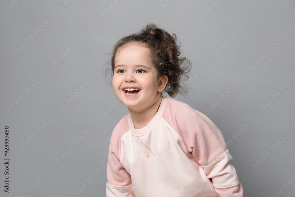 Adorable child. Portrait of happy girl on grey background. Space for text Adorable child. Portrait of happy girl on grey background. Space for text