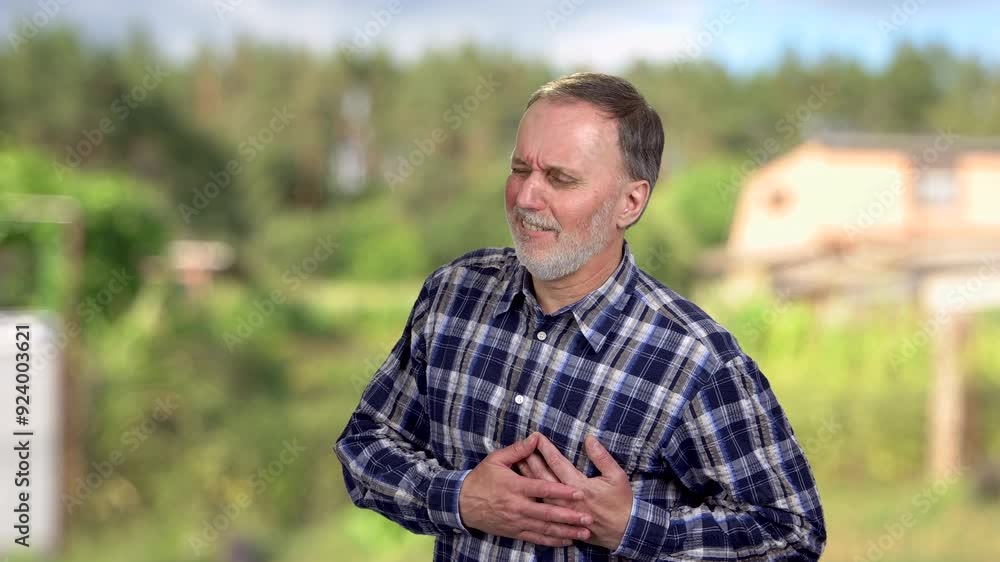 Portrait of aged senior man touching his chest having heart pain. Blurred summer countryside in the background. Portrait of aged senior man touching his chest having heart pain. Blurred summer countryside in the background.