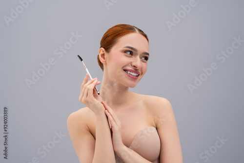 Young red-haired girl applying makeup with cosmetic brush