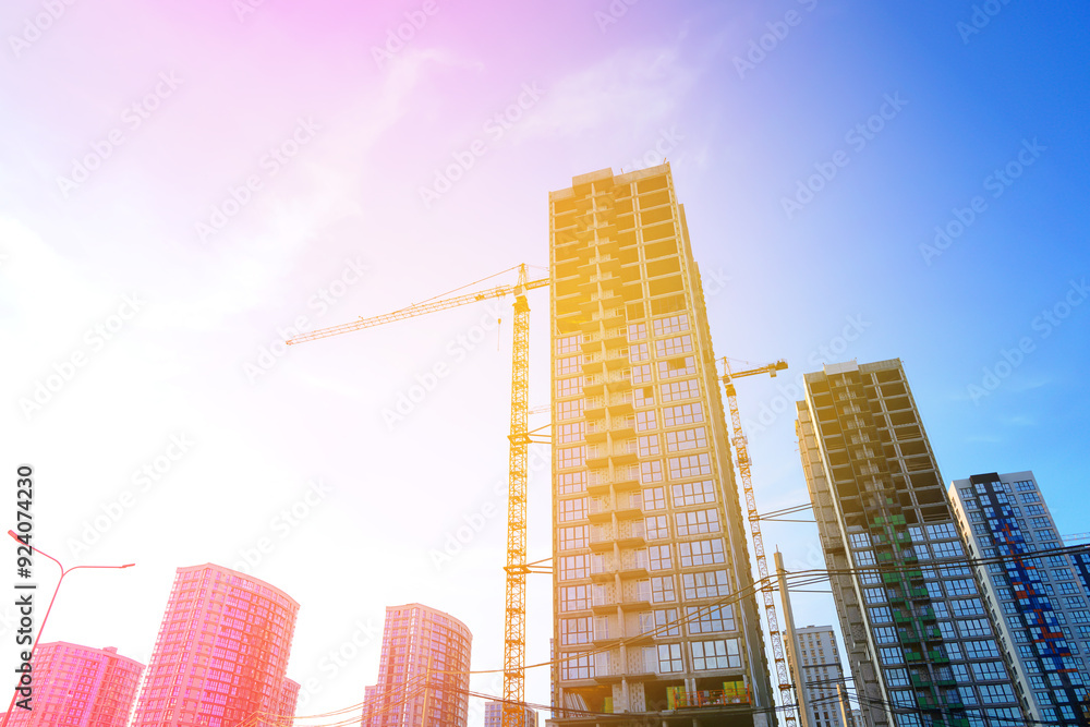 Fototapeta premium Construction site on sunset blue sky. Construction of Residential Building. Tower Crane on formworks. House Construction. Tower Cranes on Residential buildings Construction on blue sky background.