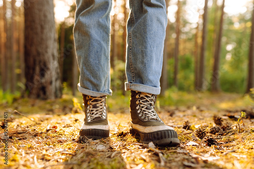 Feet of an adult wearing boots to travel walking in the forest. Feet walking in outdoor nature. Healthy lifestyle on leisure activity.