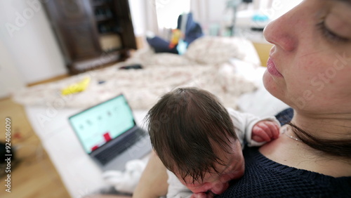 Mother closes laptop to focus entirely on her newborn baby, a tender moment of prioritizing parental care over work, highlighting the emotional bond and dedication of modern motherhood