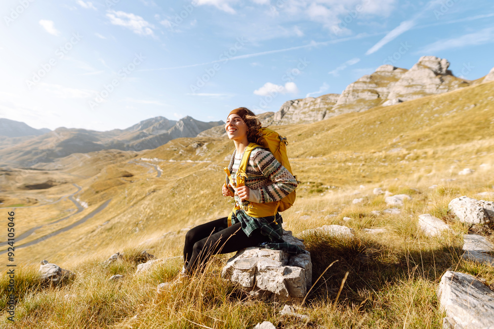 A young woman walks along a path among the dry grass. Beautiful landscape with mountains on a sunny day. Hiking. Active lifestyle A young woman walks along a path among the dry grass. Beautiful landscape with mountains on a sunny day. Hiking. Active lifestyle