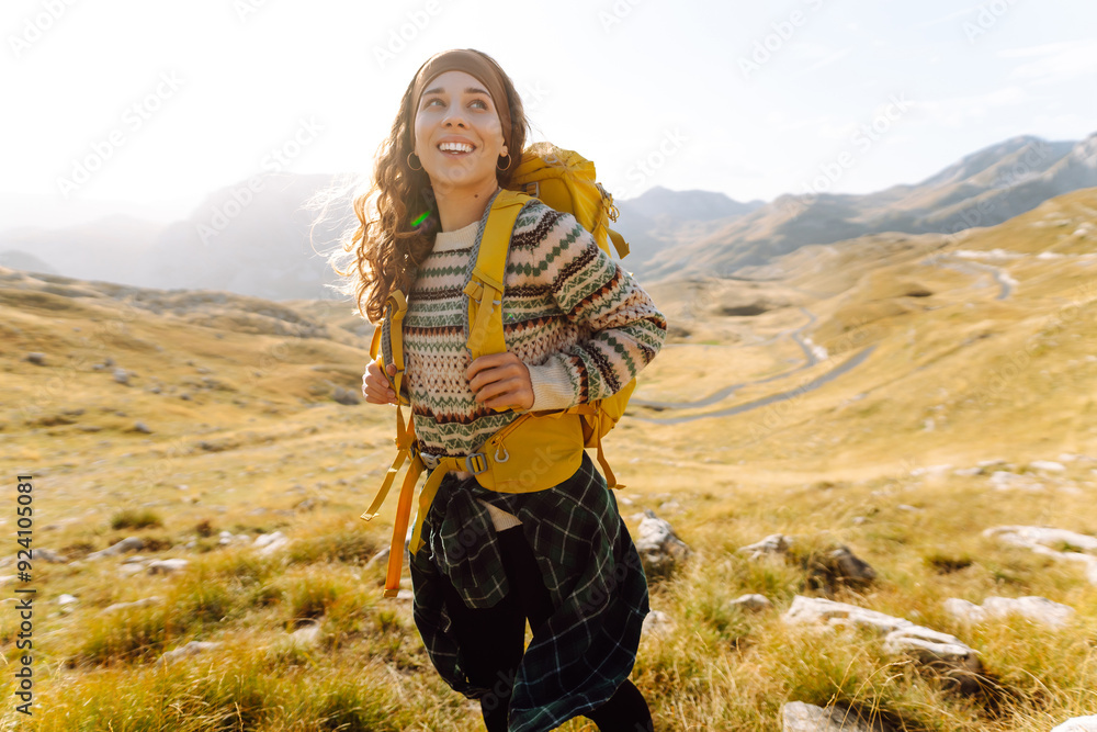 A young woman walks along a path among the dry grass. Beautiful landscape with mountains on a sunny day. Hiking. Active lifestyle A young woman walks along a path among the dry grass. Beautiful landscape with mountains on a sunny day. Hiking. Active lifestyle