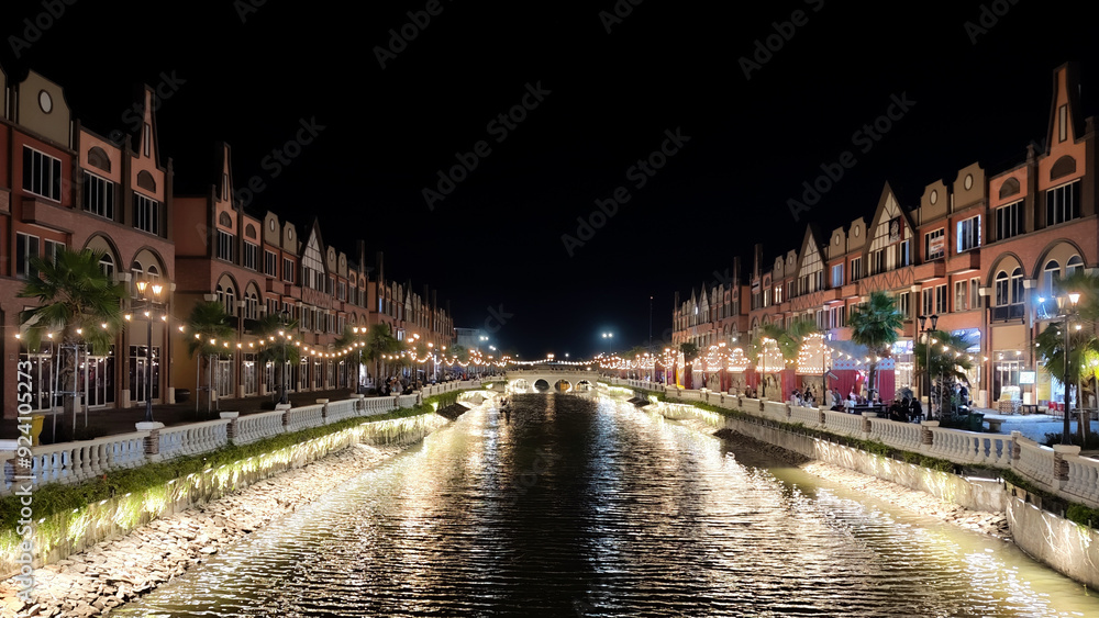 Naklejka premium Night View of European-Style Canal with Illuminated Buildings Reflected in the Water and Decorative Lights