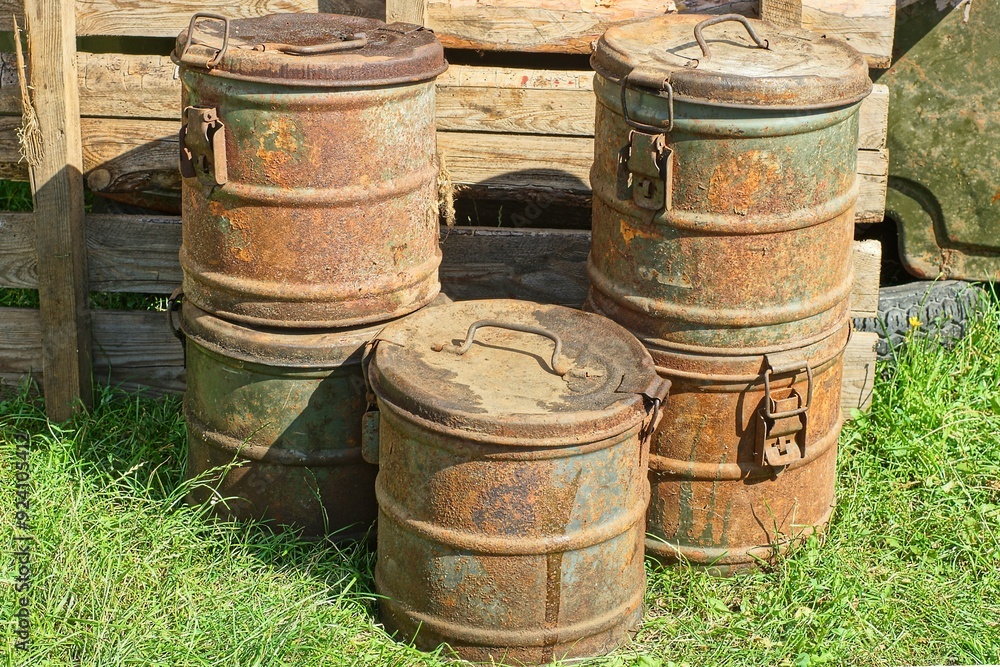 five round rusty dirty retro iron toxic closed old with lids industrial with handles and latches large containers stand on green grass during daytime outdoors five round rusty dirty retro iron toxic closed old with lids industrial with handles and latches large containers stand on green grass during daytime outdoors