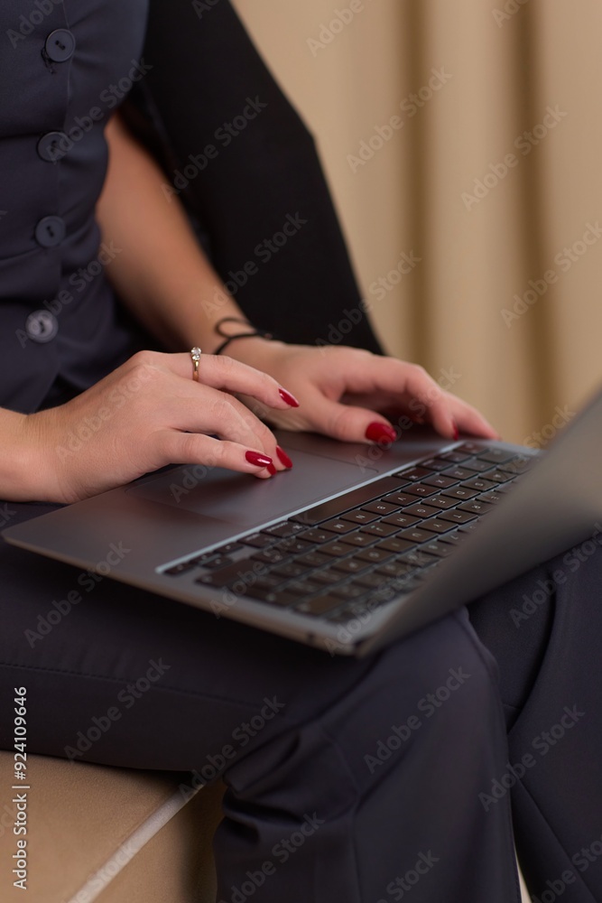 A person is seen typing on a laptop in a modern office setting with cars in the background A person is seen typing on a laptop in a modern office setting with cars in the background