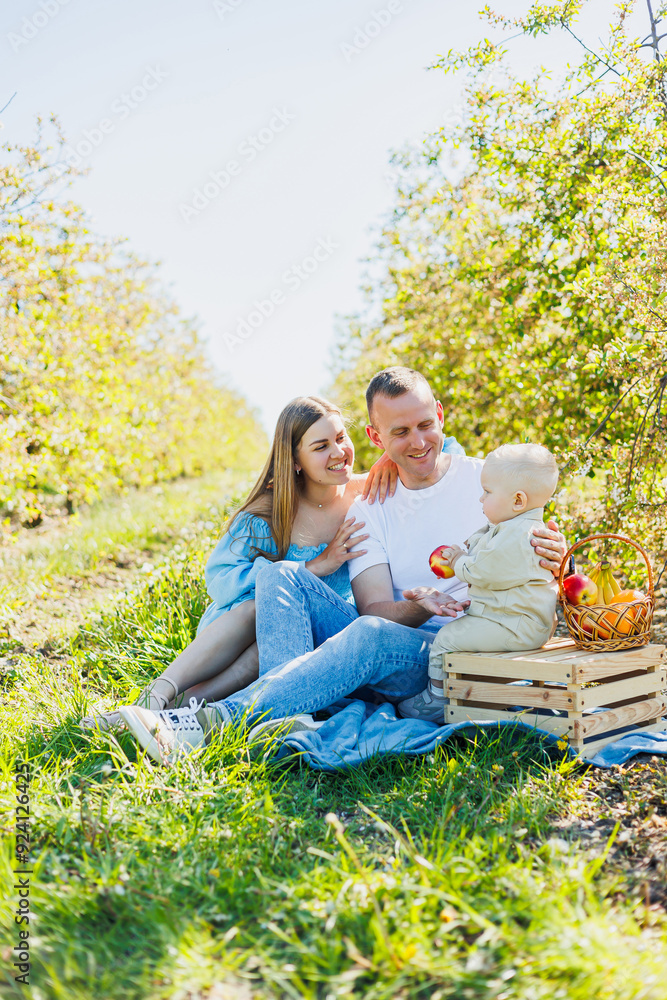 Fototapeta premium Father and mother holding little son in nature, concept of beautiful family bonds. Family portrait of parents with a little son. The concept of a happy family