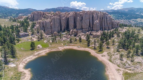   A bird's eye view of a majestic lake nestled amidst towering pine trees and a rugged rocky outcropping photo