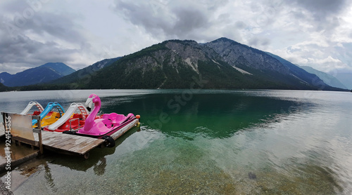 Bunte Tretboote auf dem Plansee in Österreich mit dunkler Wolkenstimmung photo