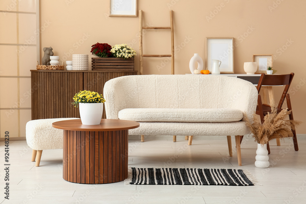 Interior of stylish living room with white sofa and chrysanthemum flowers on coffee table Interior of stylish living room with white sofa and chrysanthemum flowers on coffee table