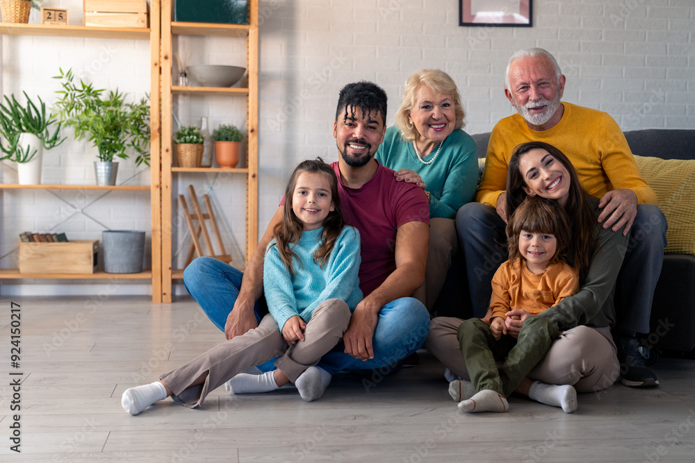 A joyful family, spanning generations, enjoys a photo session together. They smile radiantly as they pose on and around a cozy sofa in their well-furnished living room. A joyful family, spanning generations, enjoys a photo session together. They smile radiantly as they pose on and around a cozy sofa in their well-furnished living room.