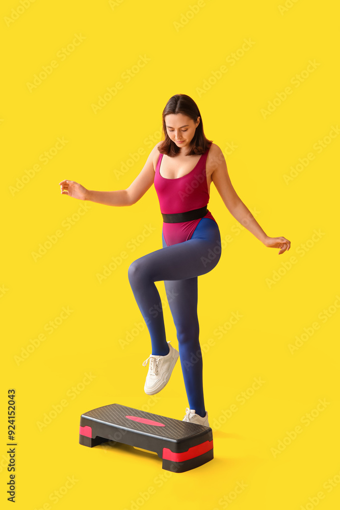 Sporty young woman training with stepper on yellow background Sporty young woman training with stepper on yellow background