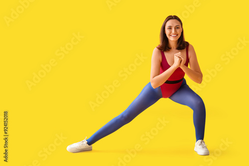 Sporty young woman training on yellow background