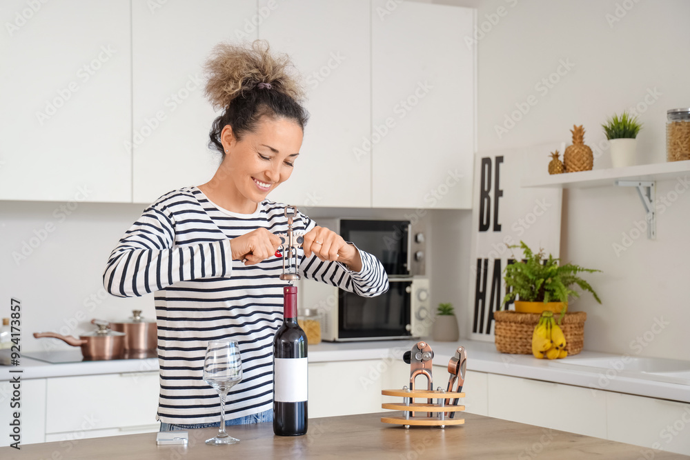 Beautiful middle-aged woman with bottle of wine taking opener at home Beautiful middle-aged woman with bottle of wine taking opener at home