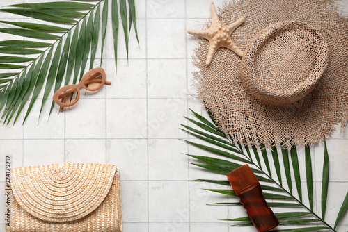 Beautiful composition with beach accessories and sunscreen on tile background