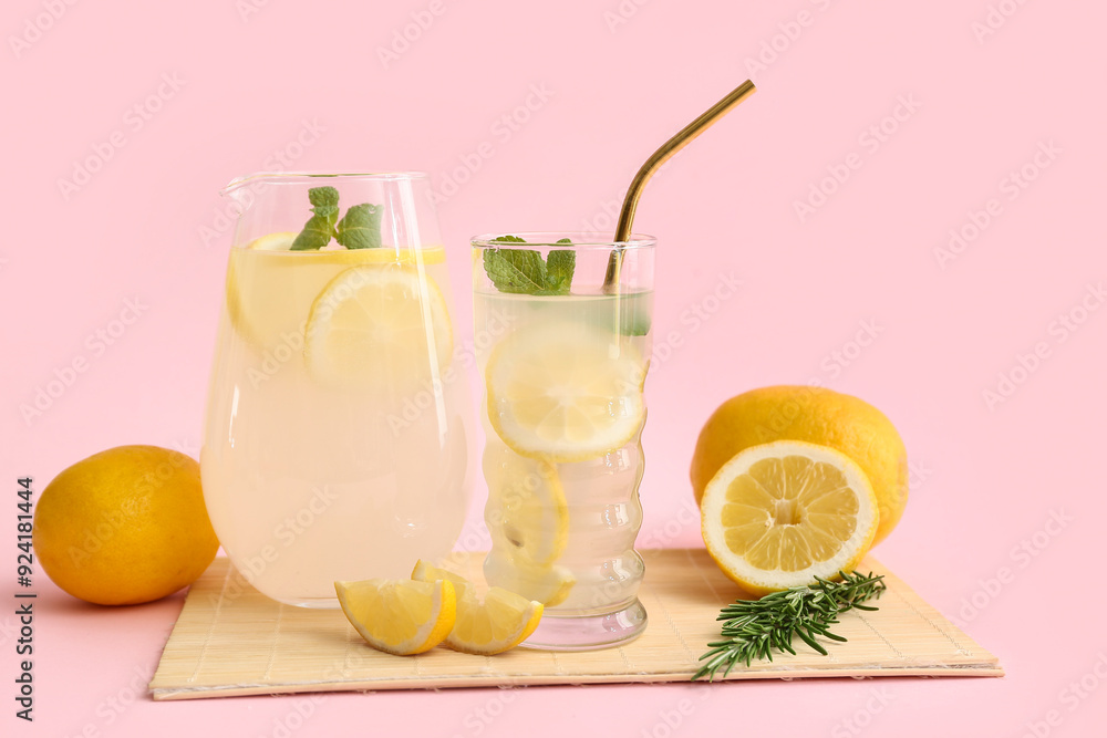 Fototapeta premium Glass and jug of fresh lemonade with mint on pink background